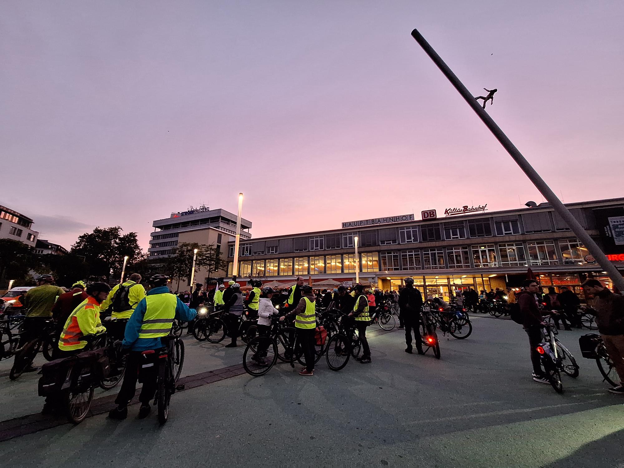 At the starting point of the Kassel Bike Night. Many people with their bikes and safety vests. In the background the sunset.