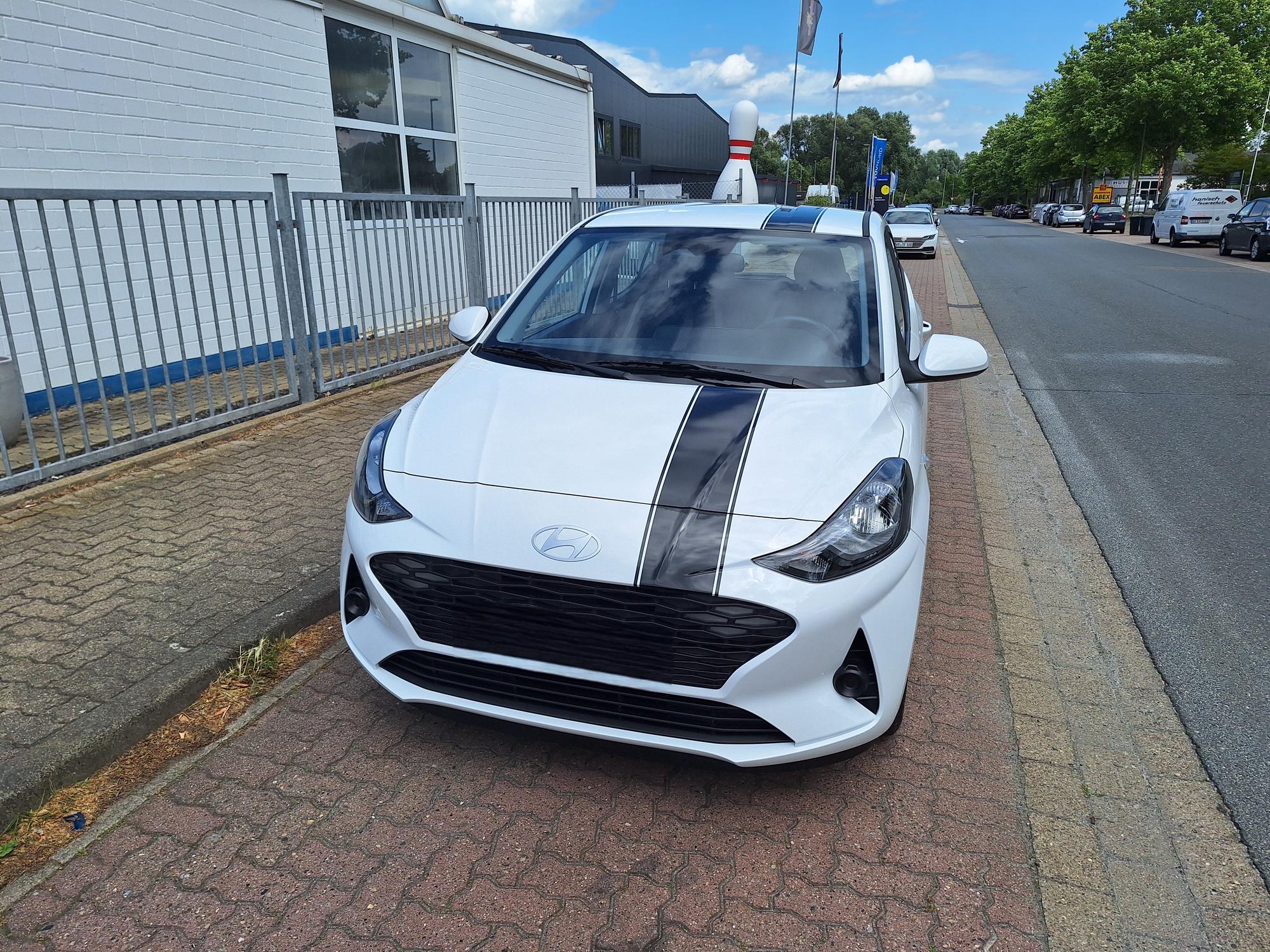 

AI generated caption: White Hyundai parked on brick pavement.