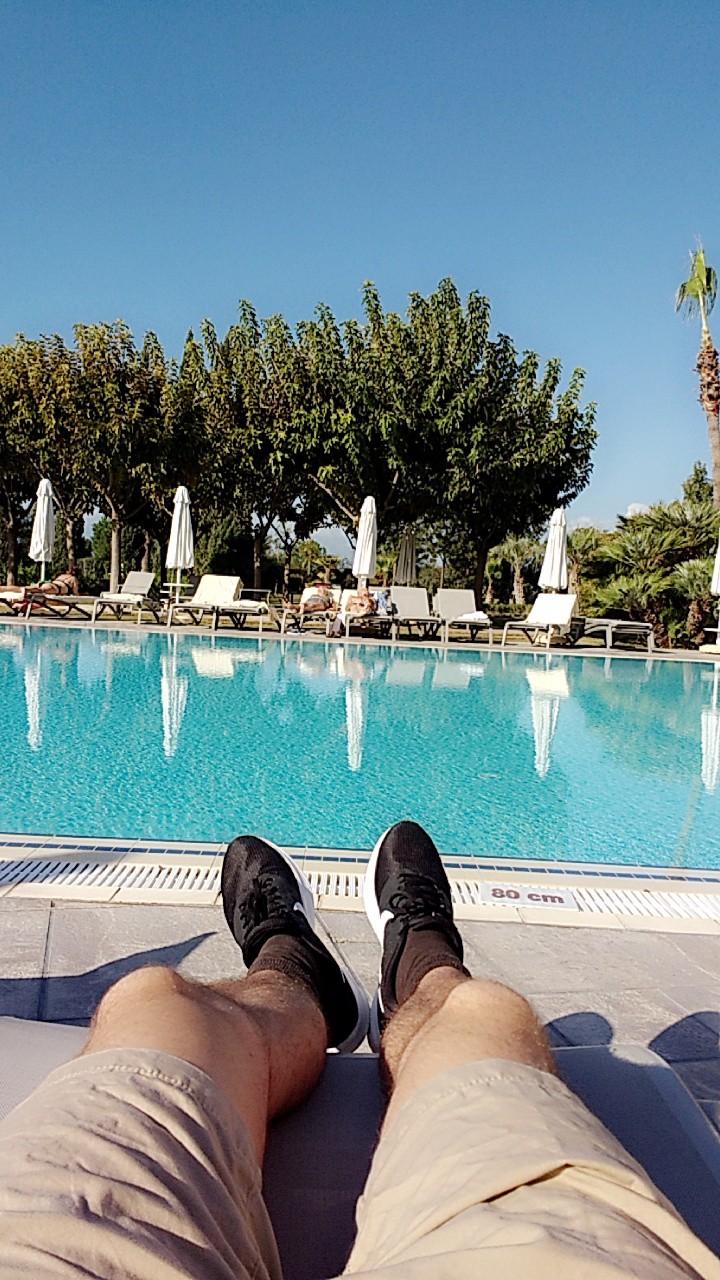 A photo showing me chilling at the pool but wearing shoes