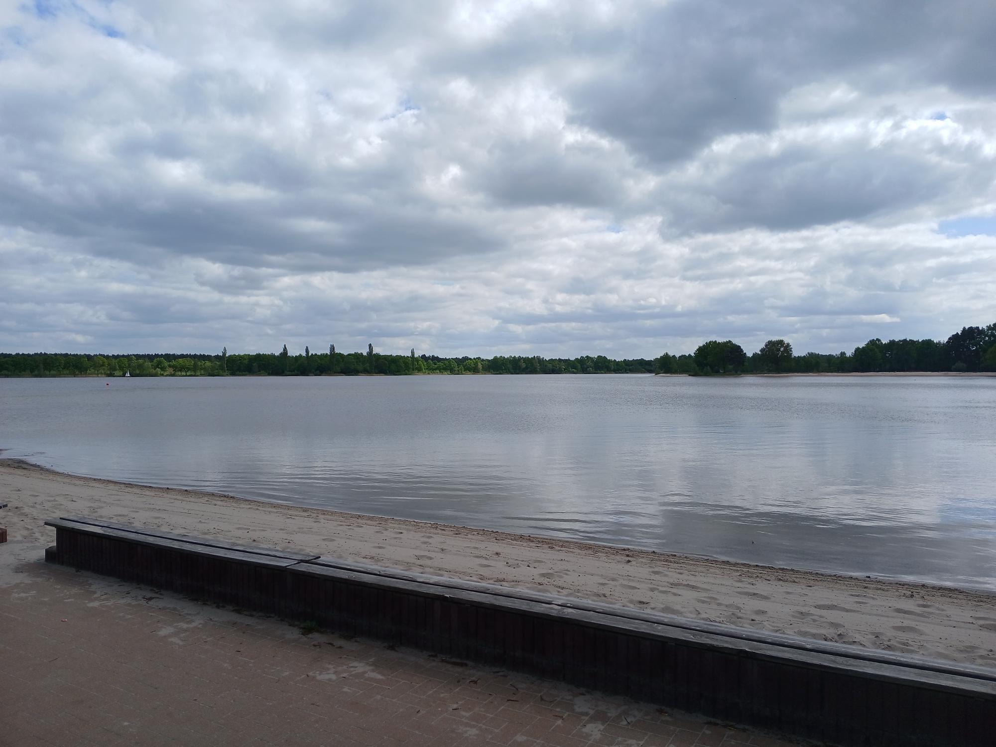

AI generated caption: Calm lake with cloudy sky and shoreline.