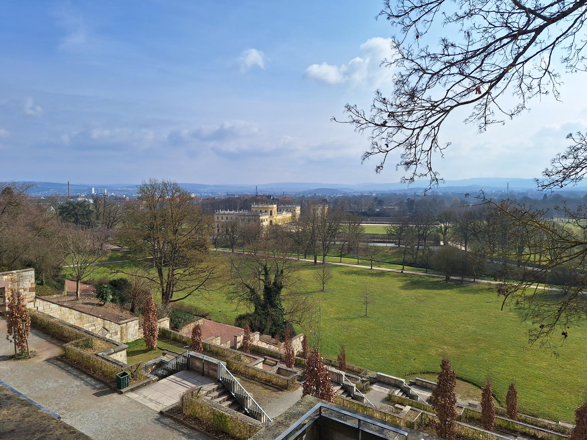 

AI generated caption: Park with open green fields and historic building in the distance.