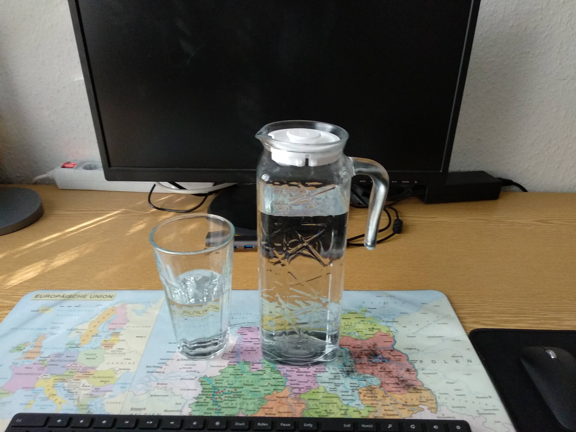A glass jug with water and a glass with water on my desk
